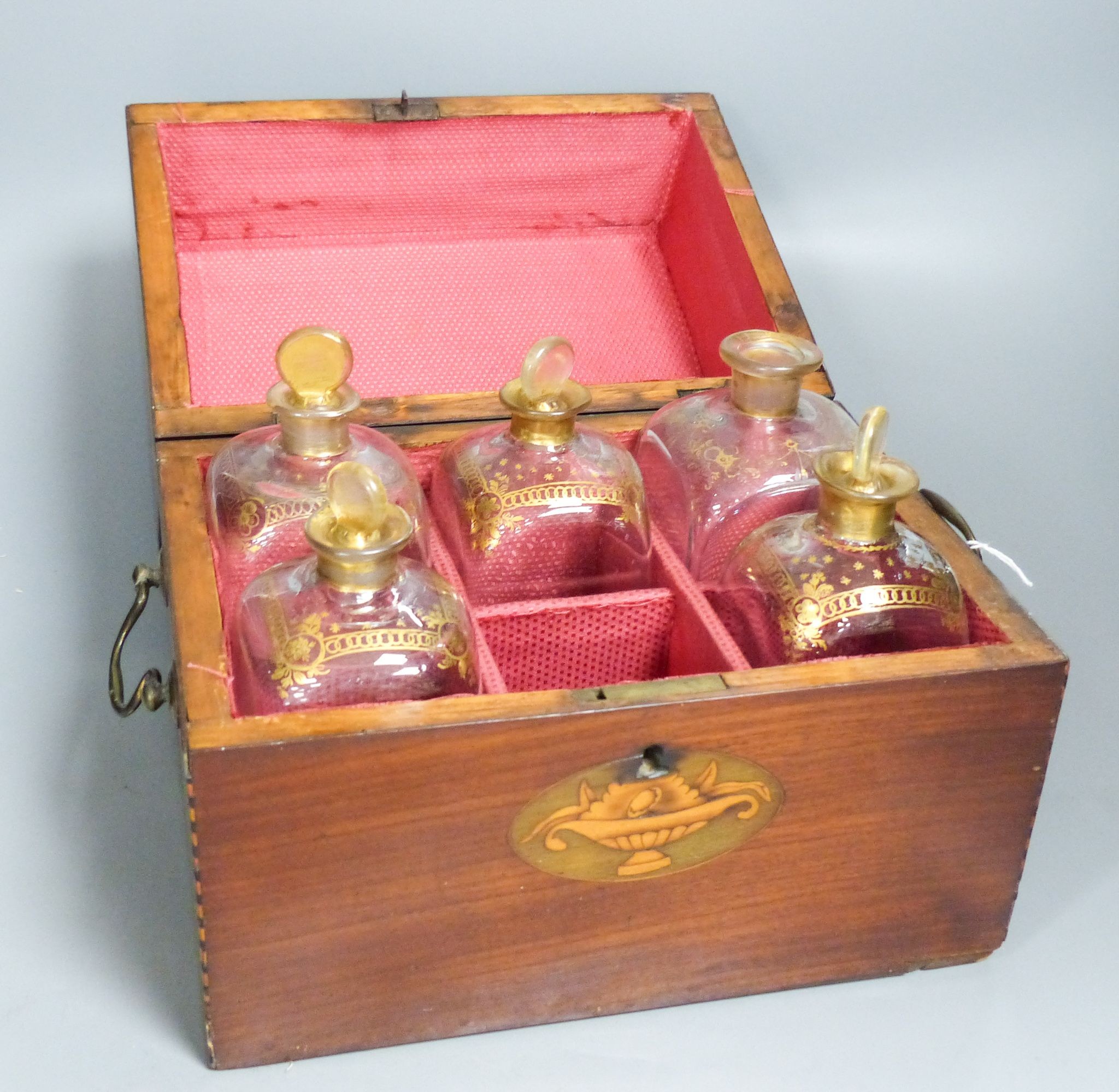 A mahogany inlaid decanter box containing five gilt decorated decanters